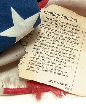 Photo: Newspaper clipping resting on American flag. Clipping has a letter home from a solider that say 'the children of Iraq will never get to see or eat at a McDonalds, BK, KFC and so forth. We should be thankful at all times.