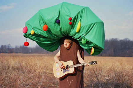 Photo: Acoustic guitarist in field wearing tree costume.