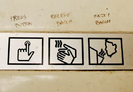 Photo: Hand dryer symbol instructions annotated with 'Press button. Receive bacon, Enjoy bacon.'