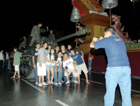 Kids posing for a photo in front of a tank at the Thai coup