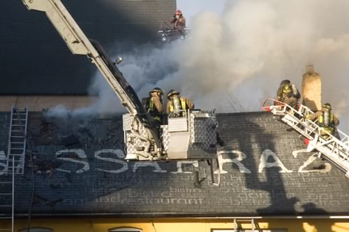 Firefighters in cherry pickers dousing the flames on the roof of Sassafraz
