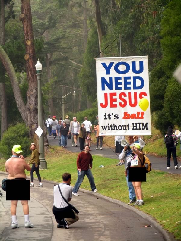 Man holding up a “You need Jesus / It’s hell without him” sign in a park as he talks to an old nudist.