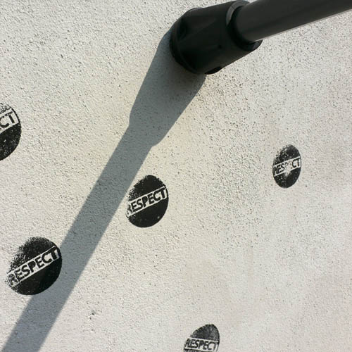 Stamping 'RESPECT' on a white wall with the 'Respect' cane.
