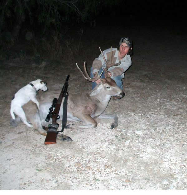 Hunter posing beside a deer he shot as his dog humps it.