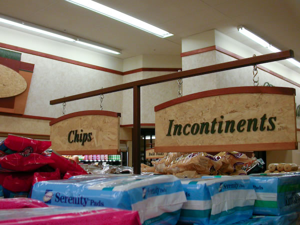 Aisle signs in a grocery store: \"Chips\" and \"Incontinents\"