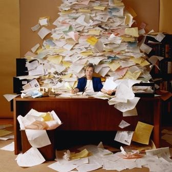 Woman at desk buried under a large pile of paperwork