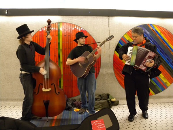 Joey deVilla playes accordion with an upright bass player and guitar player in Montreal Metro