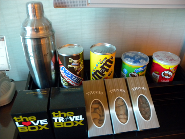 Cocktail shaker, can of Snickers miniatures, can of M&Ms, can of sour cream and chives Pringles, can of original Pringles, 3 boxes of assorted nuts, "The Love Box" and "The Travel Box"