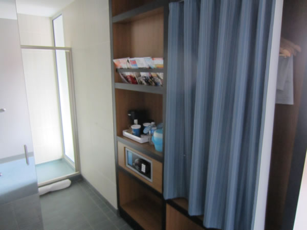 Closet area of the room, featuring curtained-off closet, magazine rack, coffee maker, ice bucket and safe