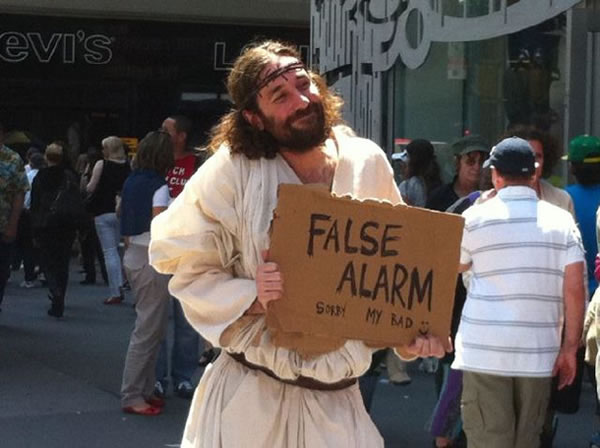 Guy dressed up as Jesus holding up a cardboard sign that reads 