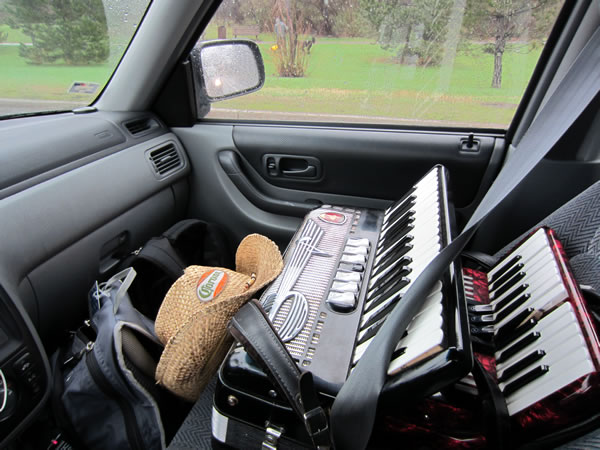 Front passenger seat of my car, with two accordions strapped in with the seatbelt.