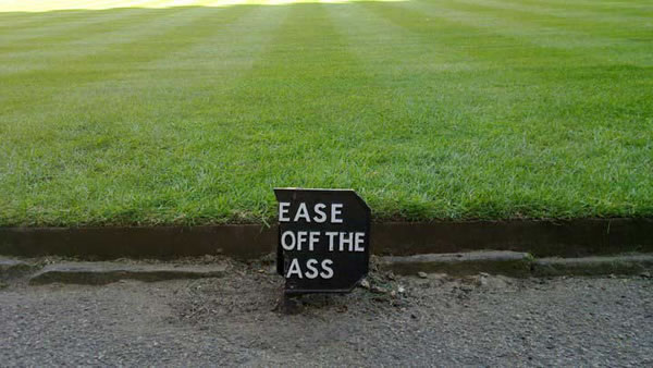 Park with 'Please keep off the grass' sign broken so that it now reads 'Ease off the ass'.