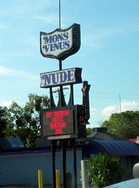 Electronic sign for the "Mons Venus Nude" strip club, which reads: "Buy American / Create American Jobs"
