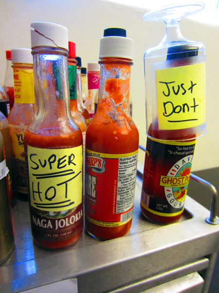 Close-up of two bottles of hot sauce, one labelled "Super HOT" and the other labelled "Just don't"