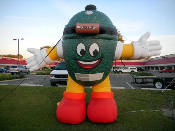 Giant balloon shaped like a "Big Green Egg" smoker, located outside a Weber barbecue dealership.