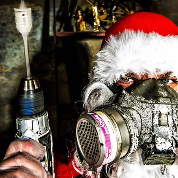 Santa wearing a filter mask and holding a drill, looking menacing