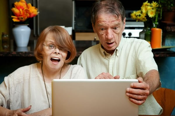 Older woman and man at a computer, looking with shocked expressions at the screen.