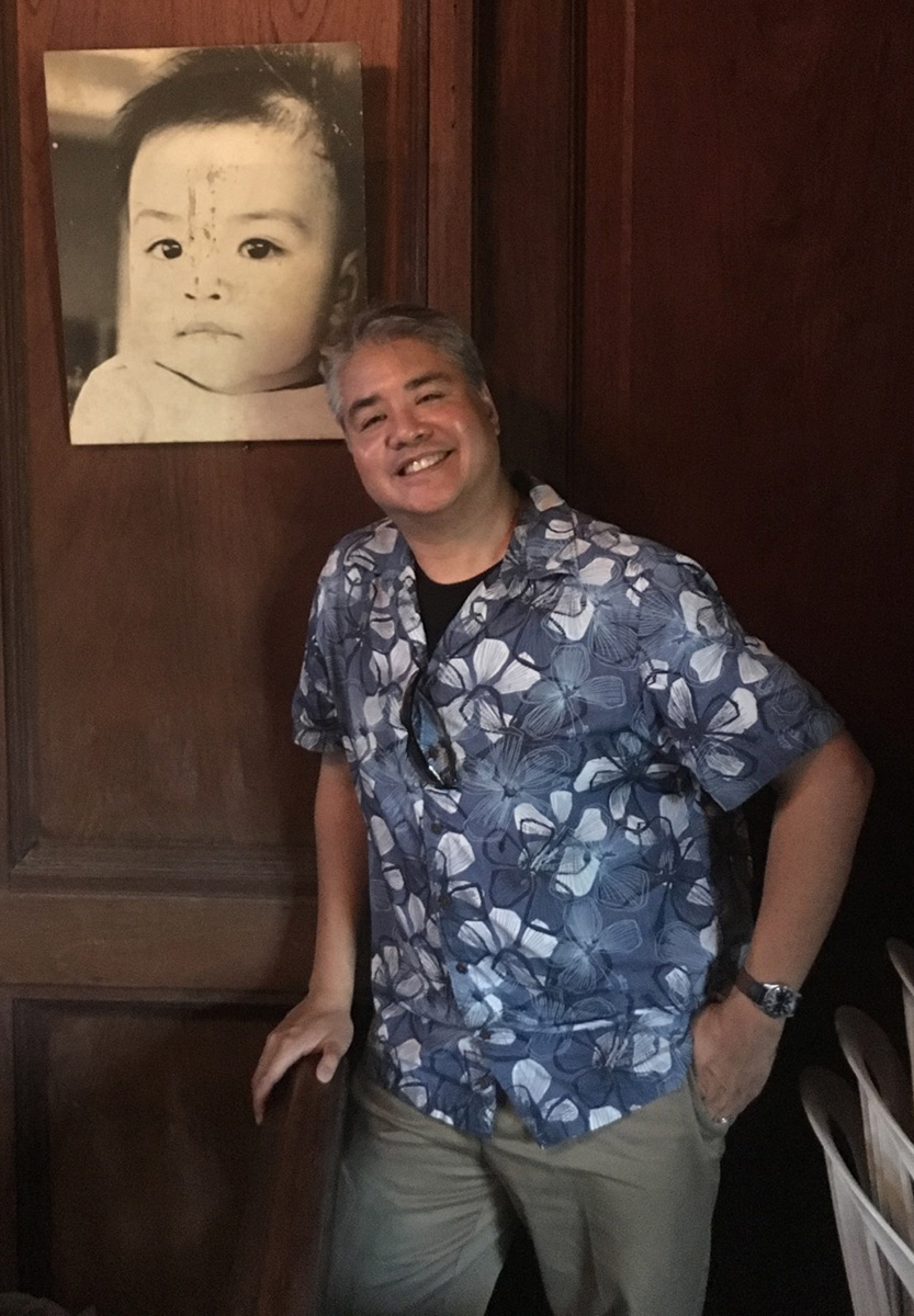 Joey deVilla posing beside his baby picture at his family’s house in San Juan, Batangas, Philippines.