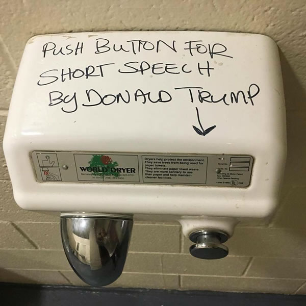 Public restroom hand dryer, with the text 'Push button for a short speech by Donald Trump' written on it.