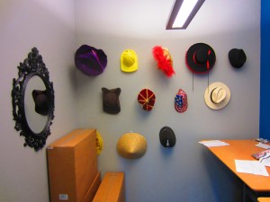 View of hat room, with the hats hanging on the wall and the mirror beside them