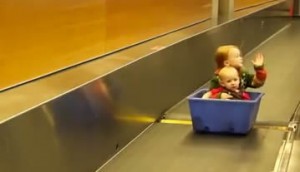 Kids riding in a bin down a luggage conveyor belt