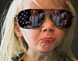 Young girl wearing mirrored sunglasses showing a reflection of Chuck Norris