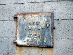 Metal plate on an exterior wall reading "New Bright Idea"
