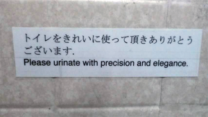 Photo: Printed signed taped to a bathroom wall that features Japanese and English text that reads 'Please urinate with precision and elegance'.