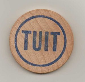 A round wooden token with the word 'TUIT' on it.