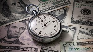 A stopwatch sitting on various denominations of US currency.