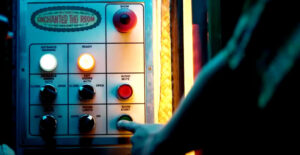 Photo: A finger pushing a button labeled “SHOW START” on a control panel labeled “ENCHANTED TIKI ROOM”.