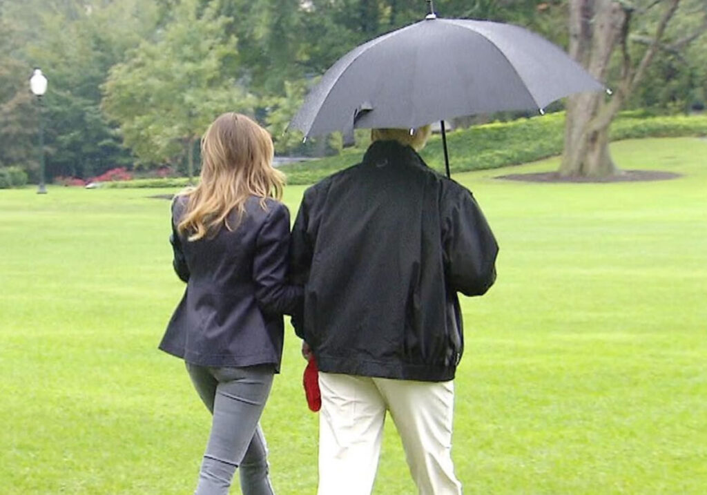 Photo: Donald and Melania Trump walking on the golf course on a misty day. Donald holds their single umbrella over himself only.