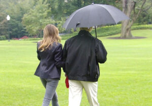 Photo: Donald and Melania Trump walking on the golf course on a misty day. Donald holds their single umbrella over himself only.