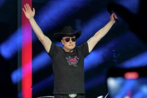 Elon Musk looking like a fatter sadder Hunter S. Thompson in a black cowboy hat and sunglasses