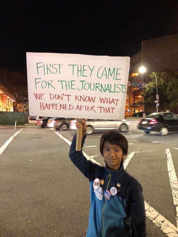 Kid holding up a sign that reads “First they came for the journalists. We don’t know what happened after that.”
