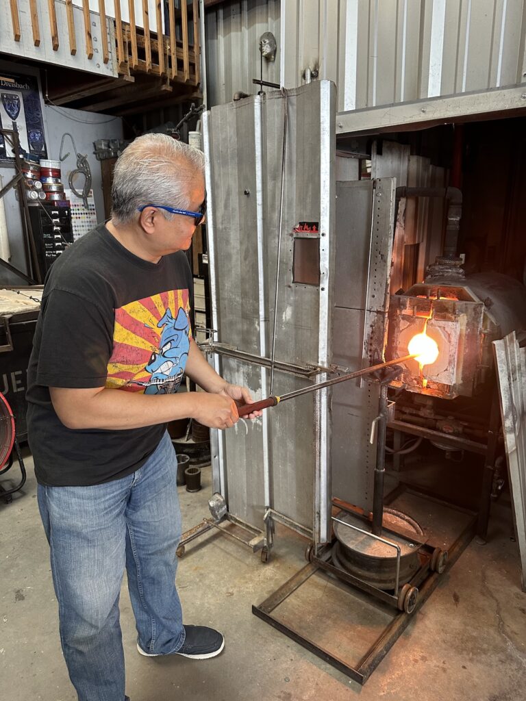 Joey deVilla spins some glass inside a glory hole at Gott Glass glassblowing studio.